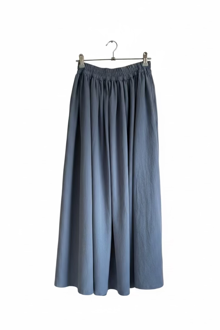 Blue skirt hanging on a hanger against a beige wall with a sewing machine below.