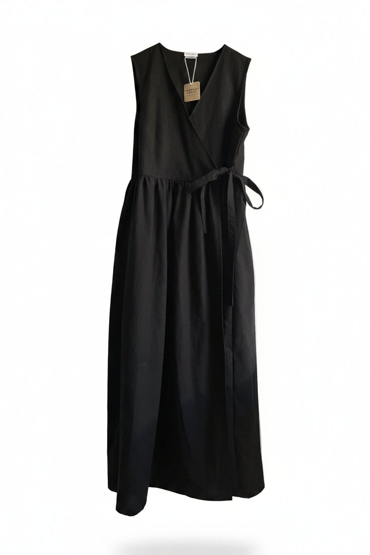 Black sleeveless dress on a hanger against a white wall